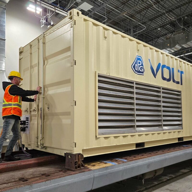 Technician inspecting VOLT battery unit during rail testing at MxV Rail facility
